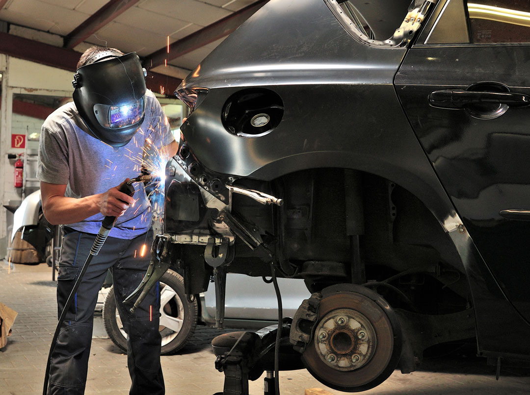 Technician working on auto body repair inside a collision repair shop